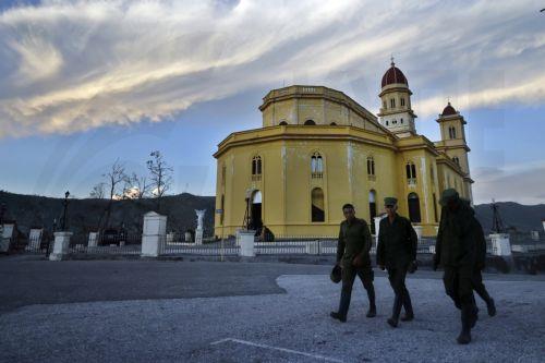 epa12511555 People walk past the Church of Our Lady of Charity in El Cobre, Santiago de Cuba province, Cuba, 07 November 2025. The five Cuban provinces severely affected by Hurricane Melissa on 29 October are beginning to gradually restore services, although authorities have warned that the damage is extensive and that normalization will take time. ...