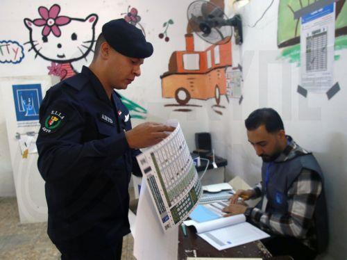 epa12513474 A member of the Iraqi security forces receives a ballot paper before voting during the early voting for the parliamentary elections, in Baghdad, Iraq, 09 November 2025. Members of the security forces and the military are casting their ballots in early voting for the Iraqi parliamentary elections before the general vote on 11 November. ...