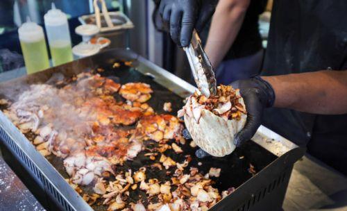 epa12522773 A employee prepares an Octopus Doener in the Pescobar restaurant in Karlsruhe, Germany, 13 November 2025. The first German branch offering octopus kebabs opened in Karlsruhe.  EPA/RONALD WITTEK