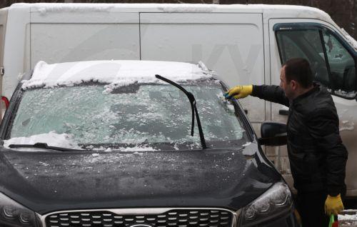 epa12531389 A man cleans his snow-covered car during a rainy autumn day at a residential area in Moscow, Russia, 17 November 2025.  EPA/MAXIM SHIPENKOV