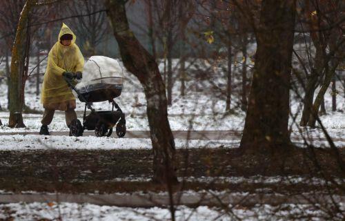 epa12531391 A woman pushes a stroller at a snow covered park during a rainy autumn day at a residential area in Moscow, Russia, 17 November 2025.  EPA/MAXIM SHIPENKOV