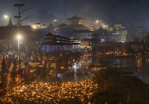 epa12534864 Nepalese devotees release oil lamps at the Bagmati River in memory of deceased family members as they observe the Balachaturdashi festival at Pashupati temple in Kathmandu, Nepal, 19 November 2025. Thousands of people from all over the country have gathered at the Pasupati temple to light oil lamps on the Bagmati River in honor of their departed...