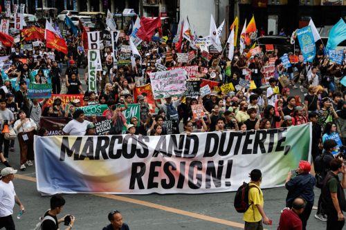 epa12539494 Protesters hold a banner calling for the resignation of Philippine President Ferdinand Marcos Jr. and Vice-President Sara Duterte during an anti-corruption rally by predominantly college-level students in Manila, Philippines, 21 November 2025. President Marcos on 21 November announced that arrest warrants have been issued for a former...