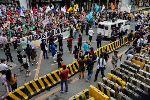 epa12539495 Protesters holding a banner calling for the resignation of Philippine President Ferdinand Marcos Jr. and Vice-President Sara Duterte approach security barricades during an anti-corruption rally by predominantly college-level students in Manila, Philippines, 21 November 2025. President Marcos on 21 November announced that arrest warrants have...