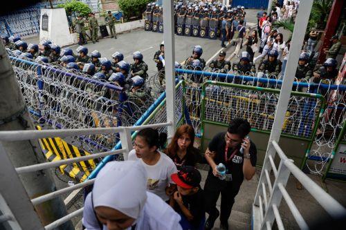 epa12539496 Philippine police keep watch from behind security barricades during an anti-corruption rally by predominantly college-level students in Manila, Philippines, 21 November 2025. President Marcos on 21 November announced that arrest warrants have been issued for a former congressman and 17 other individuals believed to be involved in anomalous...