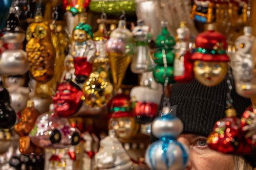 epa12562771 A vendor looks through Christmas decorations at the market in Old Town Square, Prague, Czech Republic, 01 December 2025. Christmas markets, traditionally selling mulled wine, roasted chestnuts, hot mead, chimney cakes, and Christmas decorations and gifts, opened across the Czech Republic during the first Advent weekend.  EPA/MARTIN DIVISEK
