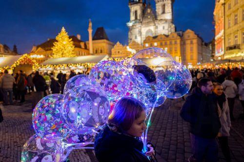 epa12562777 A vendor offers light-up balloons at the illuminated Old Town Square, with a Christmas tree and Christmas market, in Prague, Czech Republic, 01 December 2025. Christmas markets, traditionally selling mulled wine, roasted chestnuts, hot mead, chimney cakes, and Christmas decorations and gifts, opened across the Czech Republic during the first...