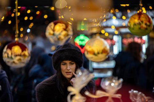 epa12562779 A visitor looks at Christmas decorations at the market in Old Town Square, Prague, Czech Republic, 01 December 2025. Christmas markets, traditionally selling mulled wine, roasted chestnuts, hot mead, chimney cakes, and Christmas decorations and gifts, opened across the Czech Republic during the first Advent weekend.  EPA/MARTIN DIVISEK