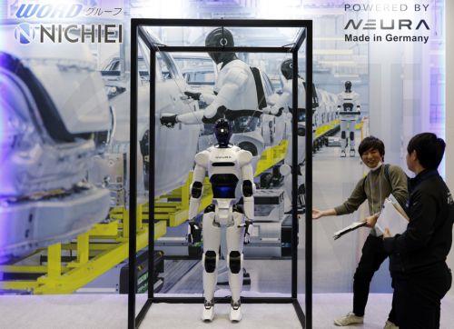 epa12566637 Visitors stand next to a humanoid robot displayed at the Neura booth during the International Robot Exhibition 2025 (iREX2025) in Tokyo, Japan, 03 December 2025. Held once every two years, the iREX is one of the world’s largest robot trade shows. For the 2025 edition, 673 companies and organizations will be presenting their latest robot...