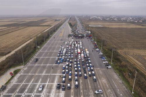 epa12566898 An aerial view taken with a drone shows the lined-up taxis, street market vendors' vehicles and tractors that have blocked the Malgara toll road, as part of the farmers' mobilization in Thessaloniki, Greece, 03 December 2025. At the Malgara toll station on the Thessaloniki–Athens National Road, farmers from the Municipality of Delta and the...