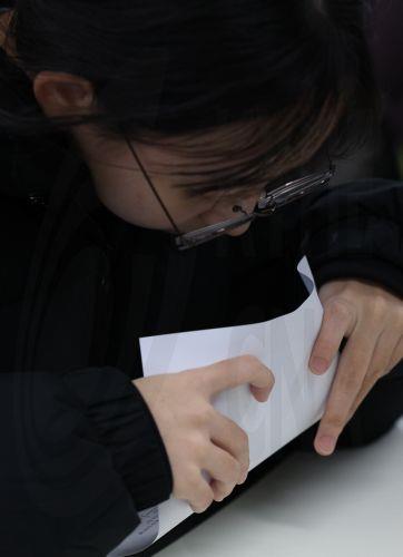 epa12570968 A senior peeps at a sheet showing her score on the state-administrated scholastic aptitude test at a girls high school in the southeastern city of Daegu, South korea, 05 December 2025. A high score on the test, administered last month, boosts a student's chances of entering their university of choice.  EPA/YONHAP SOUTH KOREA OUT