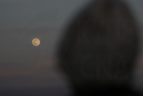epaselect epa12569900 A person looks at the supermoon shining over Sana'a, Yemen, 04 December 2025. This is the last supermoon of 2025, known as the Cold Moon.  EPA/YAHYA ARHAB