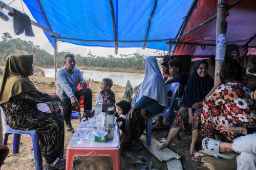 epa12578279 People sit inside a makeshift tent at a flood affected area in Aceh Tamiang, Aceh province, Indonesia, 08 December 2025. According to the National Disaster Management Agency, floods and landslides triggered by Tropical Cyclone Senyar have killed 961 people across the provinces of Aceh, North Sumatra, and West Sumatra, while 293 are reported...