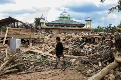 epa12578283 A man walk among logs swept away by a flash flood at a flood affected area in Aceh Tamiang, Aceh province, Indonesia, 08 December 2025. According to the National Disaster Management Agency, floods and landslides triggered by Tropical Cyclone Senyar have killed 961 people across the provinces of Aceh, North Sumatra, and West Sumatra, while 293...