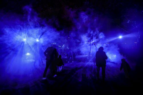 epa12609237 People visit the 'Illuminating: Nature's lights' winter light festival at Jardin des Plantes in Paris, France, 22 December 2025. The 2025 edition, which runs from 12 November through 18 January 2026, showcases the lights emitted by nature on land, in water, or in the air, whether plant, animal, or mineral.  EPA/TERESA SUAREZ