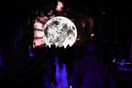 epa12609238 People enjoy a projection of the Moon during the 'Illuminating: Nature's lights' winter light festival at Jardin des Plantes in Paris, France, 22 December 2025. The 2025 edition, which runs from 12 November through 18 January 2026, showcases the lights emitted by nature on land, in water, or in the air, whether plant, animal, or mineral. ...
