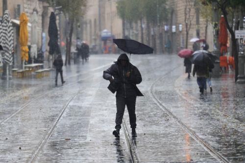 epa12616726 People walk in the rain during a stormy day in downtown Jerusalem, 29 December 2025. According to the Israel Meteorological Service, northern and central Israel, including Jerusalem, will experience occasional showers and isolated thunderstorms today, with strong westerly winds prevailing in most regions.  EPA/ABIR SULTAN