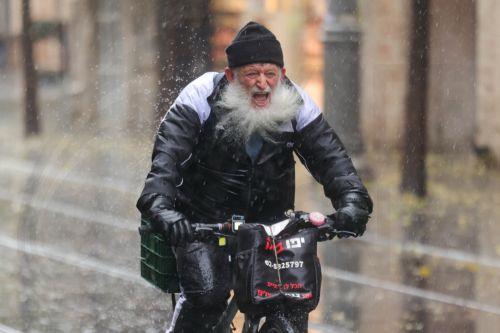 epa12616727 People walk in the rain during a stormy day in downtown Jerusalem, 29 December 2025. According to the Israel Meteorological Service, northern and central Israel, including Jerusalem, will experience occasional showers and isolated thunderstorms today, with strong westerly winds prevailing in most regions.  EPA/ABIR SULTAN