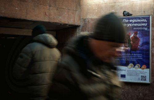 epa12616788 People walk past a euro adoption poster in Sofia, Bulgaria, 29 December 2025. Bulgaria is set to become the 21st member of the eurozone on 01 January 2026, transitioning from the national lev to the euro amid public concerns that the move could trigger immediate price hikes and a higher cost of living.  EPA/BORISLAV TROSHEV