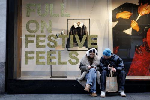 epa12616819 People sit outside a shop on Oxford Street with carrier bags as they do their winter sale shopping after Boxing Day sales in London, Britain, 29 December 2025. Early data on the morning of Boxing Day 2025 suggested a decline; however, a later evening surge pushed overall footfall across UK retail destinations, including high streets and retail...