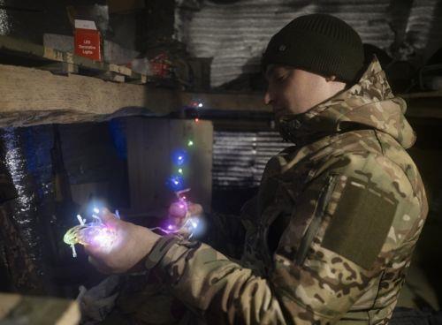 epa12618045 A handout photo made available by the press service of the 93rd 'Kholodnyi Yar' Separate Mechanized Brigade of the Ukrainian Armed Forces shows a serviceman, call sign 'Synok' (Sonny), from the brigade preparing a New Year garland at an undisclosed location near the frontline city of Kostyantynivka, Donetsk region, eastern Ukraine, 30 December...
