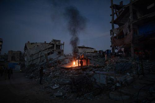 epa12618094 Displaced Palestinians warm themselves near a fire among the ruins of their destroyed home in Khan Yunis, southern Gaza Strip, 30 December 2025, amid a ceasefire between Israel and Hamas.  EPA/HAITHAM IMAD