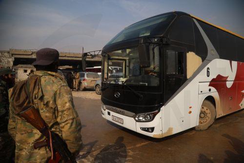 epa12637785 A soldier stands next to one of the buses waiting to evacuate the Kurdish-led Syrian Democratic Forces (SDF) fighters from Aleppo, northern Syria, 09 January 2026. The Syrian Ministry of Defense announced a ceasefire agreement in the neighborhoods of Sheikh Maqsoud, Ashrafieh, and Bani Zaid of Aleppo allowing the withdrawal of members of the SDF...