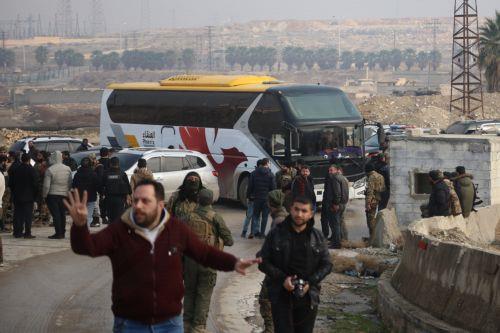 epa12637788 People stand near one of the buses waiting to evacuate the Kurdish-led Syrian Democratic Forces (SDF) fighters from Aleppo, northern Syria, 09 January 2026. The Syrian Ministry of Defense announced a ceasefire agreement in the neighborhoods of Sheikh Maqsoud, Ashrafieh, and Bani Zaid of Aleppo allowing the withdrawal of members of the SDF...