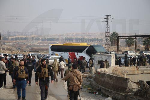 epa12637789 Soldiers stand near one of the buses waiting to evacuate the Kurdish-led Syrian Democratic Forces (SDF) fighters from Aleppo, northern Syria, 09 January 2026. The Syrian Ministry of Defense announced a ceasefire agreement in the neighborhoods of Sheikh Maqsoud, Ashrafieh, and Bani Zaid of Aleppo allowing the withdrawal of members of the SDF...