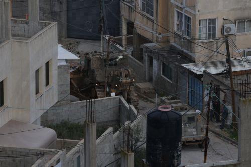 epa12644862 Palestinians watch Israeli army bulldozers during a military operation in Nur Shams refugee camp, near the West Bank city of Tulkarem, 12 January 2026. Israeli troops continue their operation in the Nur Shams refugee camp, east of Tulkarem, which has been under a tight Israeli siege since January 2025.  EPA/ALAA BADARNEH