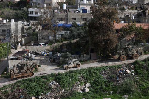 epa12644863 Israeli army bulldozers and armored vehicles pass buildings during a military operation in Nur Shams refugee camp, near the West Bank city of Tulkarem, 12 January 2026. Israeli troops continue their operation in the Nur Shams refugee camp, east of Tulkarem, which has been under a tight Israeli siege since January 2025.  EPA/ALAA BADARNEH