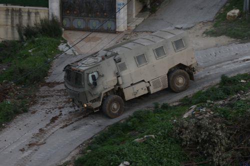 epa12644873 An Israeli army troop vehicle drives by during a military operation in Nur Shams refugee camp, near the West Bank city of Tulkarem, 12 January 2026. Israeli troops continue their operation in the Nur Shams refugee camp, east of Tulkarem, which has been under a tight Israeli siege since January 2025.  EPA/ALAA BADARNEH