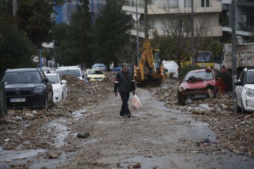 epa12670795 A resident walks amidst damaged and buried cars after a storm swept the area in Glyfada, near Athens, Greece, 22 January 2026. The violent weather that swept the country on 21 January left two people dead and caused extensive damage and infrastructure problems, mainly in Attica.  EPA/YANNIS KOLESIDIS
