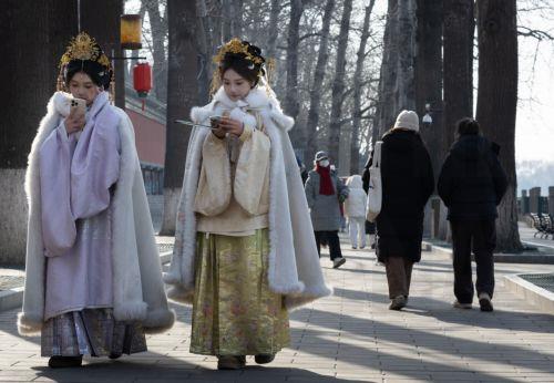 epa12681822 People dressed in traditional clothing walk at a park in Beijing, China, 26 January 2026. In Beijing, tourists can purchase services such as traditional clothing rental, make-up application, hair up-dos, and photography to enhance their cultural experience of the city.  EPA/JESSICA LEE