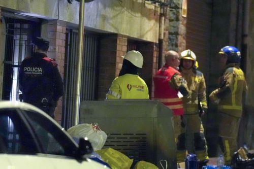 epa12748828 A policeman and firefighters stand outside the building where a fire broke out in the town of Manlleu, Barcelona, northeastern Spain, late 16 February 2026 (issued 17 February 2026). At least five teenagers died and four other people were injured in the fire which started in a storage room located on the roof of the building.  EPA/SIU WU