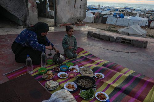 epa12774676 A displaced Palestinian woman prepares iftar in the remains of a destroyed building among makeshift tents before breaking their fast during the holy month of Ramadan, near the beach in Gaza City, 24 February 2026. Muslims around the world celebrate the holy month of Ramadan by praying during the nighttime and abstaining from eating, drinking,...