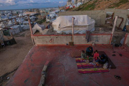 epa12774706 A displaced Palestinian family breaks fast at sunset in the remains of a destroyed building among makeshift tents during the holy month of Ramadan, near the beach in Gaza City, 24 February 2026. Muslims around the world celebrate the holy month of Ramadan by praying during the nighttime and abstaining from eating, drinking, and sexual acts...