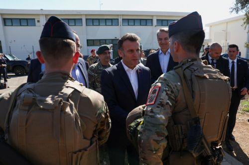 epa12806507 French President Emmanuel Macron (C) speaks to members of the military next to Cypriot President Nikos Christodoulides (C-L, partially hidden), and Greek Prime Minister Kyriakos Mitsotakis (C-R) at Paphos military airport, in Paphos, Cyprus, 09 March 2026, on the day of Macron's visit to show France's solidarity after recent drone attacks amid...