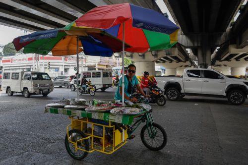 epa12808247 A snacks vendor on a tricycle crosses an intersection in Quezon City, Metro Manila, Philippines, 10 March 2026. As significant fuel price hikes hit the Philippines 10 March amidst ongoing Middle East tensions from conflict involving the United States, Israel and Iran, bicycles are expected to be used as alternative modes of transport by...