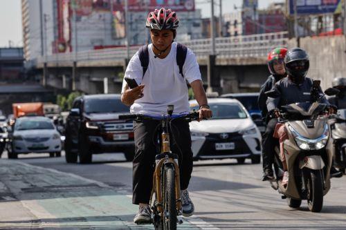 epa12808248 A person on a bicycle looks at his mobile phone while travelling along a main thoroughfare in Quezon City, Metro Manila, Philippines, 10 March 2026. As significant fuel price hikes hit the Philippines 10 March amidst ongoing Middle East tensions from conflict involving the United States, Israel and Iran, bicycles are expected to be used as...