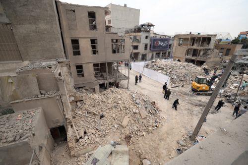epa12821309 Iranians walk amid damaged residential buildings in southern Tehran, Iran, 15 March 2026. A joint Israeli and US military operation continues to target multiple locations across Iran since the early hours of 28 February 2026.  EPA/ABEDIN TAHERKENAREH